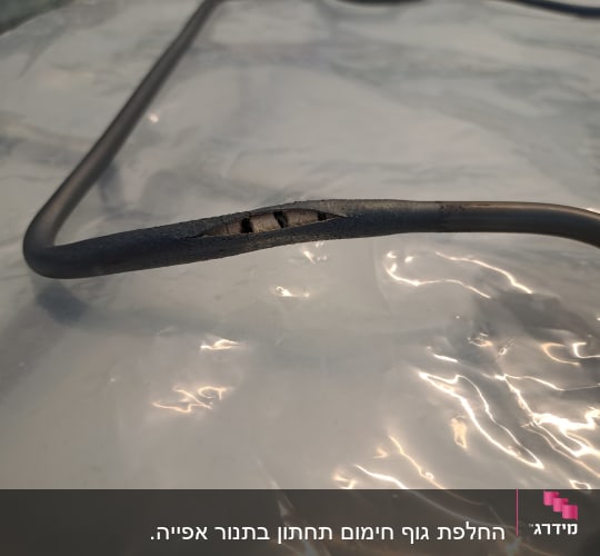 כבל חשמלי עם בידוד פגום על רקע פלסטיק שקוף